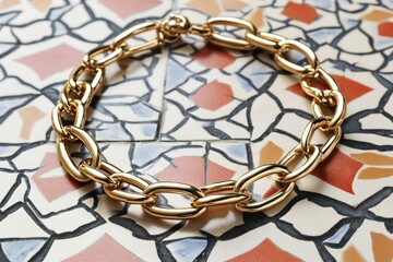 A modern display of an artificial gold link bracelet on a geometric-patterned tile, blending contemporary art and jewelry.