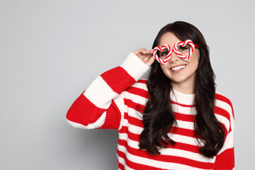 Happy woman with party glasses on light grey background, space for text. Christmas celebration