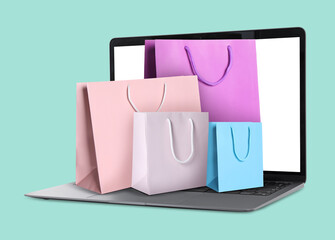 Laptop with shopping bags on turquoise background. Concept of online shopping, purchase via internet