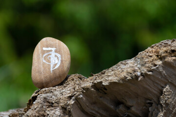 A close up image of a reiki healing symbol painted on a smoothly polished rock. 