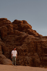 Man walking on rocks in the desert of the wadi rum in jordan at sunset