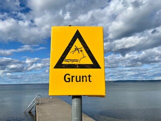 Warnschild vor flachem Wasser am Vätternsee in Schweden