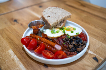 Breakfast with fried eggs, bacon and toasts on a white plate with cup of coffee on a stone background. Top view, selective focus. High quality photo