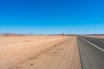 Road in middle of desert near Hurghada Egypt. Empty Asphalt road against blue sky