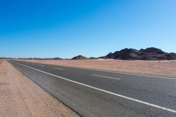 Road in middle of desert near Hurghada Egypt. Empty Asphalt road against blue sky