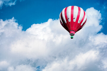 Obraz premium Red and white hot air balloon on the background of bright blue cloudy sky.