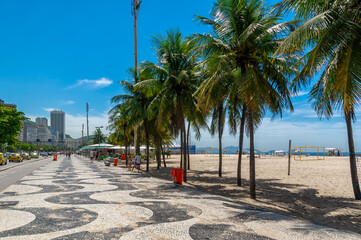 Copacabana beach with palms and mosaic of sidewalk in Rio de Janeiro, Brazil. Copacabana beach is the most famous beach in Rio de Janeiro. Sunny cityscape of Rio de Janeiro