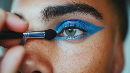 bearded man transgender applying eyeshadow with make-up brush on eye , making makeup. 