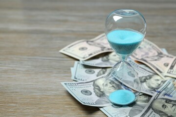 Modern hourglass with dollar bills
on wooden background. Hourglass time concept for business deadline, urgency and outcome of time