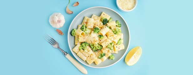 Plate of tasty pasta with broccoli on blue background