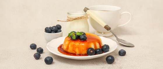 Plate with delicious pudding and blueberries covered by caramel syrup on white grunge background