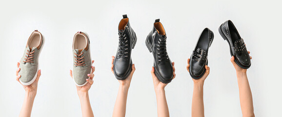 Hands with stylish shoes on white background