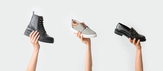 Hands with stylish shoes on white background