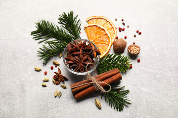 Different spices, dried orange slices and fir tree branches on light grey table. Christmas season