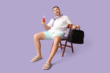 Happy office worker with cocktail and briefcase sitting on chair against lilac background
