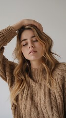 A Caucasian woman with wavy long hair shows signs of sadness while seated indoors in a minimalistic space