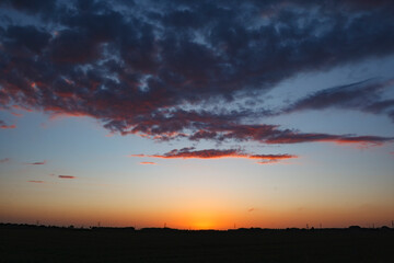Beautiful sunset over a tranquil landscape with colorful clouds reflecting warm hues in the evening...