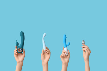 Female hands with different vibrators and anal plug on blue background