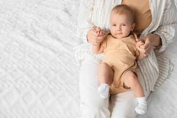 Mother with her little baby sitting on bed, closeup
