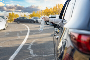 Girl throws plastic bottle out of car, ecological concept