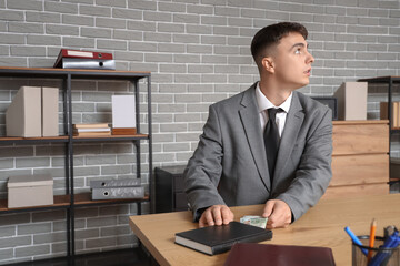 Young businessman hiding bribe in notebook at office. Corruption concept