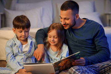 Fototapeta premium Young father reading bedtime story for cute little children at home