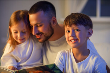 Father and little children reading bedtime story before going to sleep