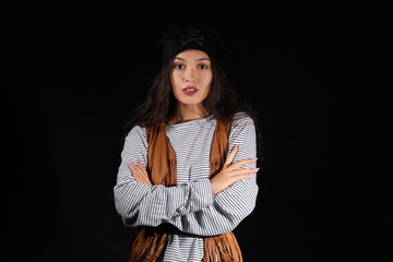 Beautiful young Asian woman dressed as pirate on black background