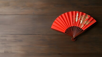 Decorative red fan placed elegantly on a wooden surface showcasing traditional craftsmanship and design elements