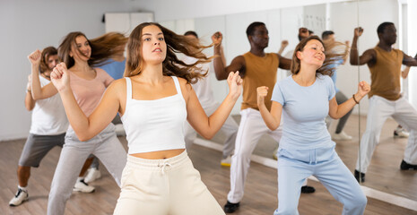Fototapeta premium Energetic women and man performing modern dance in fitness studio