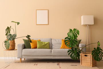 Cozy sofa, lamp and Monstera houseplants in interior of living room