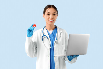 Female Asian endocrinologist with thyroid gland model and laptop on blue background