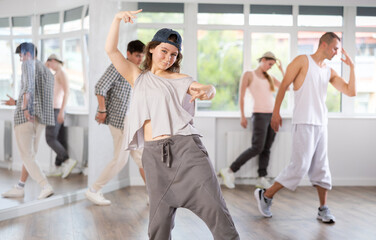 Fototapeta premium Group of energetic hip-hop dancers focused on training while gathered together in spacious dance hall