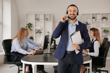 Male technical support agent with headset and clipboard in office