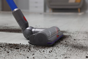 Cleaning floor with cordless vacuum cleaner indoors, closeup