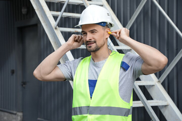 Male builder putting in earplugs outdoors