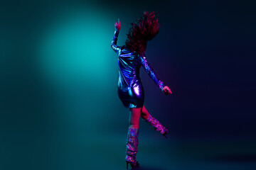 Full body rear portrait of stunning young girl have good mood dance wear shiny dress neon light dark blue background