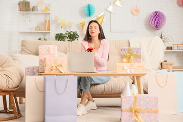 Happy young woman in party hat with muffin celebrating Birthday online at home