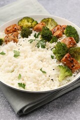 Tasty rice with broccoli, chicken and parsley on grey table, closeup