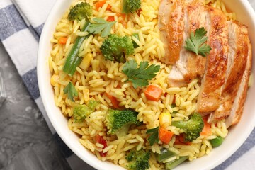 Tasty rice with vegetables and chicken on table, top view