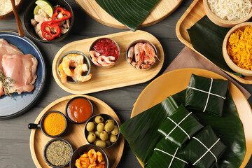 Different food wrapped in banana leaves, products, sauce and spices on wooden table, flat lay