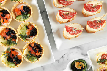 Many different tasty canapes on white marble table, flat lay