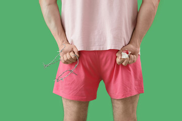 Suffering man with barbed wire and bloodstained toilet paper on green background. Hemorrhoid concept