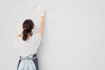 Female worker with putty knife near light wall, back view