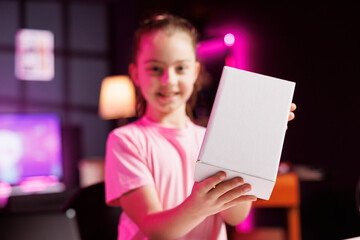 Portrait of young content creator filming herself unboxing product popular among children watching...