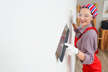 Female decorator with putty knife working near light wall in room