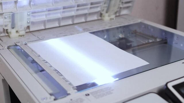 An office worker scans a sheet of A4 paper on a scanner