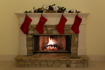 Four red Christmas stockings on a beautiful stone fireplace in a residence.