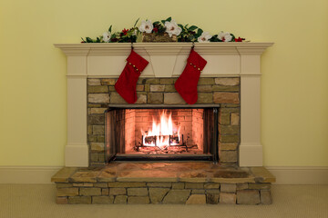 Two red stockings grace a stone fireplace in a cozy living room at holiday time.