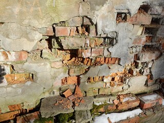 Textured background of old weathered red bricks on uneven wall of outdoor house with dirty worn plaster